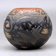 A black bowl with a sienna rim and spots decorated around with a sgraffito avanyu, bear paw and geometric design, plus an inlaid stone, click or tap to see a larger version