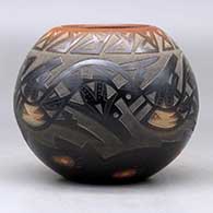 A black bowl with a sienna rim and spots decorated around with a sgraffito avanyu, bear paw and geometric design, plus an inlaid stone, click or tap to see a larger version