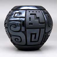 A matte and polished black jar decorated with a four-panel carved spiral, bear, feather and geometric design, click or tap to see a larger version