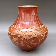 A large red low shouldered jar with a flared rim and decorated with a carved avanyu, feather and geometric design
 by Sharon Naranjo Garcia of Santa Clara