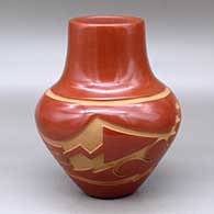 A red jar decorated with a carved avanyu and geometric design around the shoulder
 by Sherry Tafoya of Santa Clara