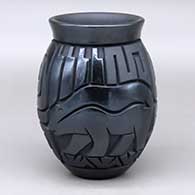 A black on black jar decorated with a carved and painted black bear, spirit bear, feather, cloud, spiral, flower and geometric design
 by Harrison Begay Jr of Santa Clara