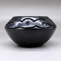 A black bowl carved above the shoulder with an avanyu and geometric design, click or tap to see a larger version