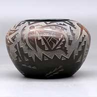 A black bowl decorated with sienna spots and a sgraffito hummingbird, butterfly and geometric design, click or tap to see a larger version