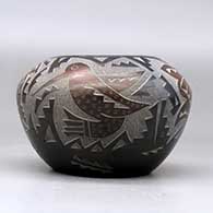 A black bowl decorated with sienna spots and a sgraffito hummingbird, butterfly and geometric design, click or tap to see a larger version