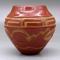 A red jar carved with an avanyu and geometric design around the body, click or tap to see a larger version