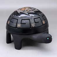 A polished and micaceous black turtle with sienna spots and decorated with a carved and sgraffito hummingbird, flower, vine and geometric design, plus seven inlaid stones
 by Melony Gutierrez of Santa Clara