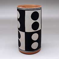 A polychrome cylinder decorated with a checkerboard and dot geometric design
 by Thomas Tenorio of Santo Domingo