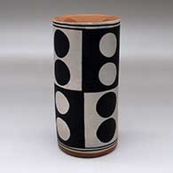 A polychrome cylinder decorated with a checkerboard and dot geometric design
 by Thomas Tenorio of Santo Domingo