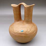 A golden micaceous wedding vase with a lightly carved avanyu design with a piece of turquoise for its eye
 by Dora Tse Pe of San Ildefonso