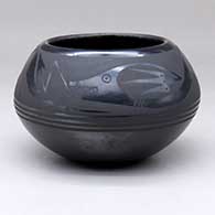 A black-on-black bowl decorated with an avanyu and geometric design above the shoulder
 by Johnny Cruz of San Ildefonso