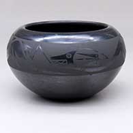 A black-on-black bowl decorated with an avanyu and geometric design above the shoulder
 by Johnny Cruz of San Ildefonso