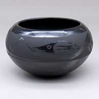 A black-on-black bowl decorated with an avanyu and geometric design above the shoulder
 by Johnny Cruz of San Ildefonso