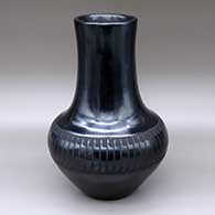 A tall, black-on-black vase with a ring of feathers design around the shoulder
 by Maria Martinez of San Ildefonso