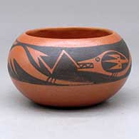 A small black on red bowl decorated with an avanyu and cloud formation geometric design
 by Johnny Cruz of San Ildefonso