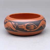 A black on red bowl decorated with an avanyu and rain cloud geometric design
 by Johnny Cruz of San Ildefonso