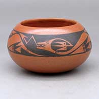 A black on red bowl decorated with an avanyu, rain cloud and geometric design
 by Johnny Cruz of San Ildefonso