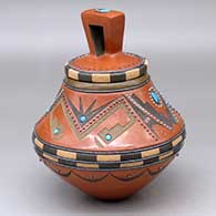 A lidded polychrome jar decorated with a four-panel geometric design plus multiple inlaid pieces of Kingman and Red Mountain turquoise and Sleeping Beauty hematite dots
 by Russell Sanchez of San Ildefonso