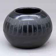 A black on black bowl decorated with a ring of feathers design around the shoulder
 by Santana Martinez of San Ildefonso