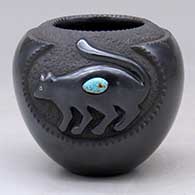 A matte and polished black jar decorated with a carved mountain lion with an inlaid stone
 by Russell Sanchez of San Ildefonso