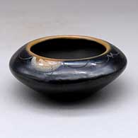 A small black bowl with a sienna rim and spots and decorated above the shoulder with a sgraffito geometric design
 by Barbara Gonzales of San Ildefonso