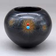 A small black jar with sienna spots, two inlaid stones and decorated with a sgraffito spider, web, flower and geometric design
 by Barbara Gonzales of San Ildefonso