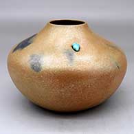 A golden micaceous jar with fire clouds and an inlaid piece of turquoise
 by Angie Yazzie of Taos