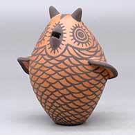 A black on red owl figure decorated with bird element appliques and design, click or tap to see a larger version