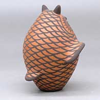 A black on red owl figure decorated with bird element appliques and design, click or tap to see a larger version