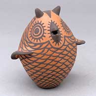 A black on red owl figure decorated with bird element appliques and design
 by Carlos Laate of Zuni