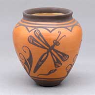 A small black on red jar decorated with a three panel dragonfly, tadpole and geometric design
 by Carlos Laate of Zuni