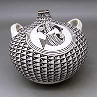 A large black on white canteen with handles and decorated with a crane and fish medallion surrounded by a spiral mesa geometric design