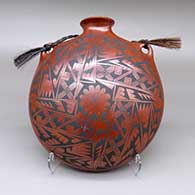A polychrome canteen with a flared opening, a geometric design, and a braided horsehair handle